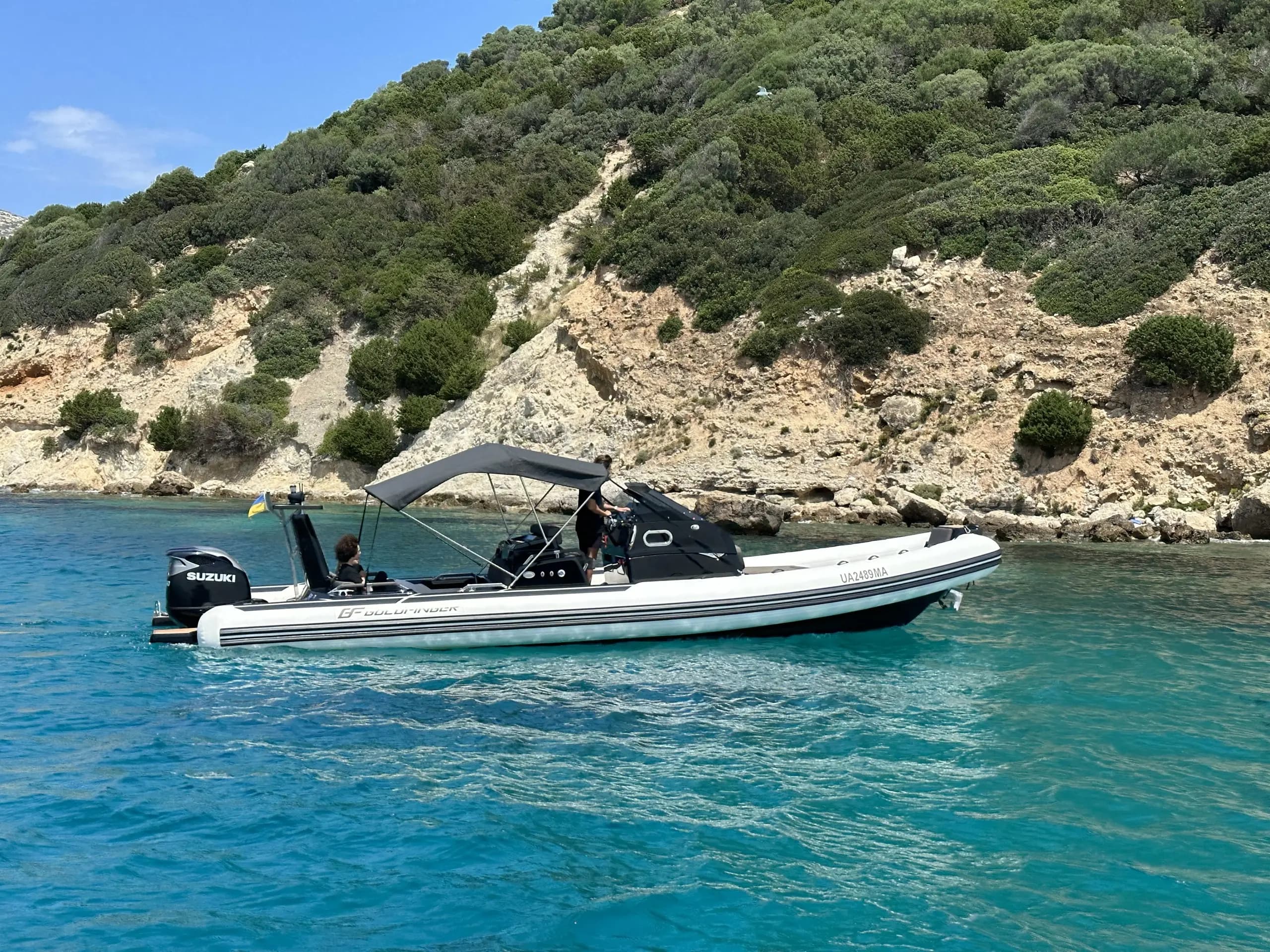 Brig Eagle 10 anchored near rocky Sardinian coastline with bimini shade