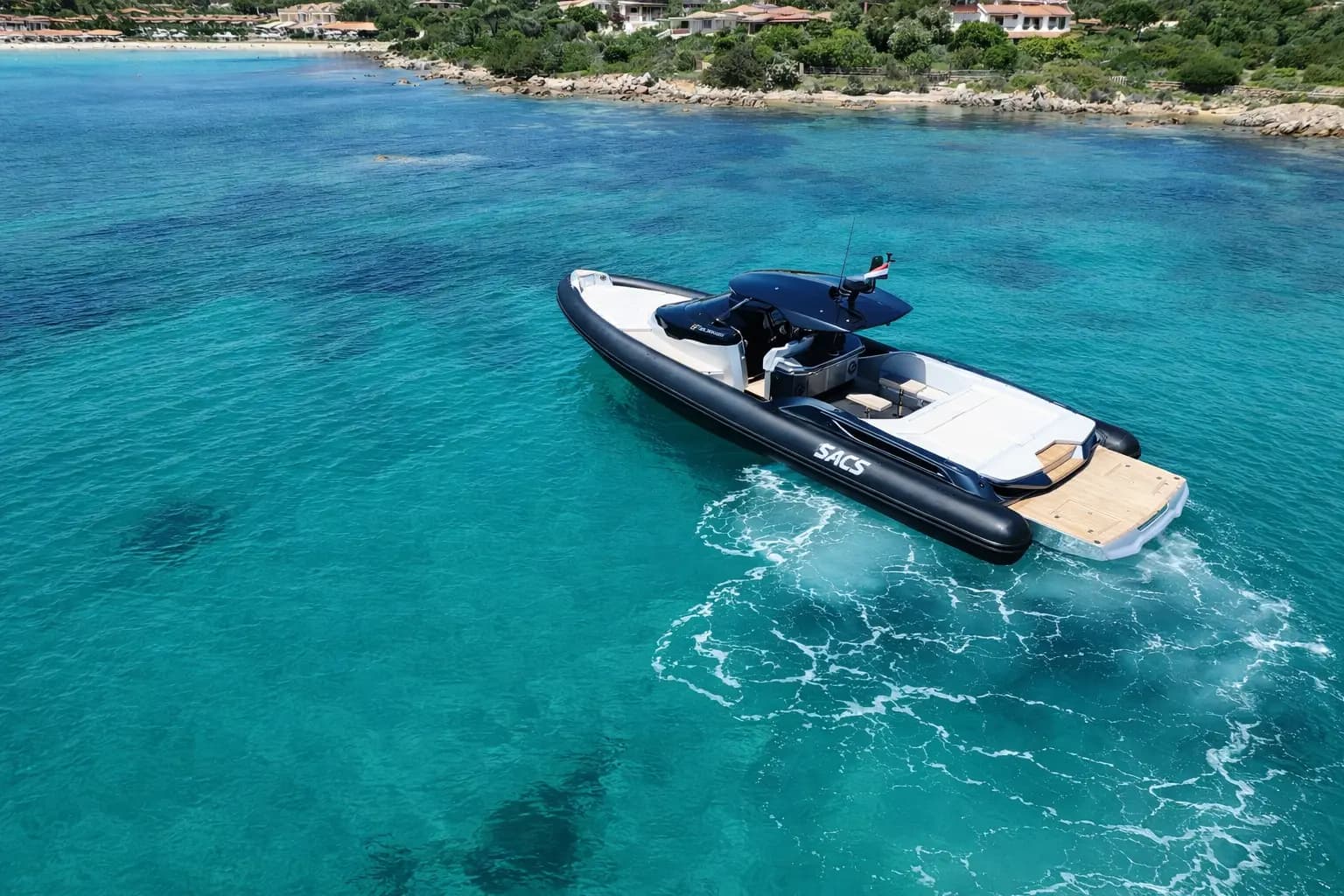 Aerial view of SACS Strider 15 RIB anchored in turquoise Sardinian shallows